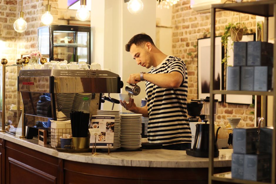 Barista pripravlja kavo za pultom v kavarni Zrnela
